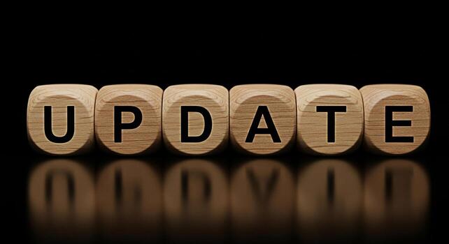 Wooden blocks spelling UPDATE on a reflective surface against a dark background symbolizing software updates information updates and the importance of staying current with the latest information and t photo