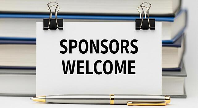 Sponsors welcome message displayed on a white card with binder clips placed in front of a stack of books and a pen creating a welcoming and supportive atmosphere for potential partners photo