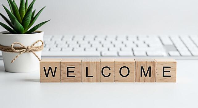 Wooden blocks spelling Welcome on a white desk next to a potted succulent plant and a computer keyboard creating a warm and inviting atmosphere for visitors and new beginnings photo