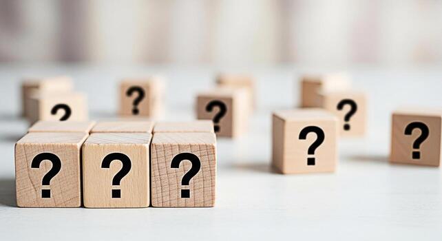 Wooden blocks displaying question marks on a white surface representing uncertainty and the search for answers in a bright minimalist setting evoking curiosity and the unknown photo