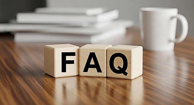 Wooden blocks spelling FAQ on a polished wooden desk with a white mug and blurred books representing frequently asked questions and a helpful informative atmosphere for customer support photo