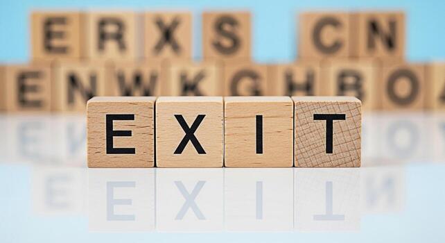 Wooden blocks spelling EXIT on a reflective surface suggesting a strategic departure from a challenge or project symbolizing a new beginning and a fresh start in a bright minimalist setting photo