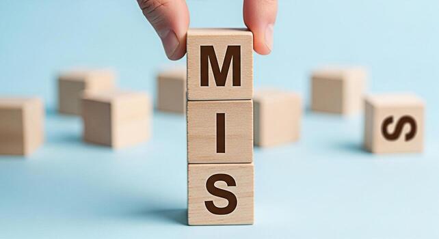 Hand arranging wooden blocks spelling MIS on a blue surface representing Management Information Systems in a conceptual and educational setting emphasizing data analysis and strategic decisionmaking photo