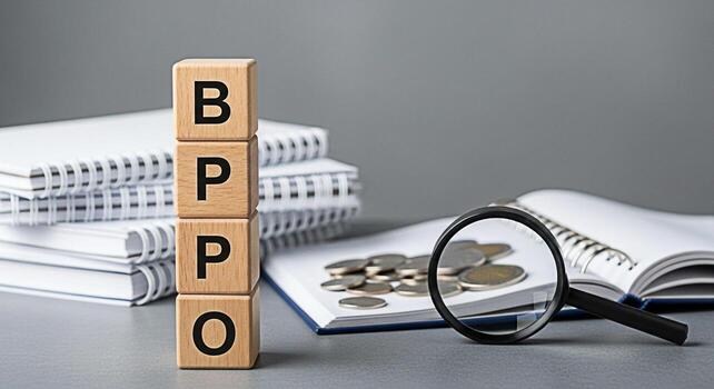 Wooden blocks spelling BPPO are stacked near coins and a magnifying glass on a notebook representing business process outsourcing in a financial setting creating a concept of efficiency and cost reduc photo