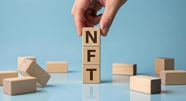 Hand stacking wooden blocks spelling NFT on a blue surface representing the concept of nonfungible tokens and digital assets in the modern financial technology and blockchain environment photo