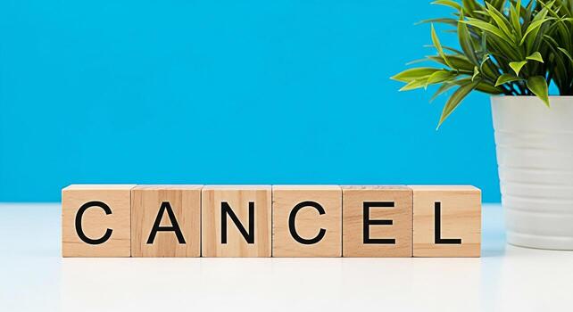 Wooden blocks spelling CANCEL on a white table against a vibrant blue background conveying a message of termination cancellation or ending with a sense of finality and resolution photo