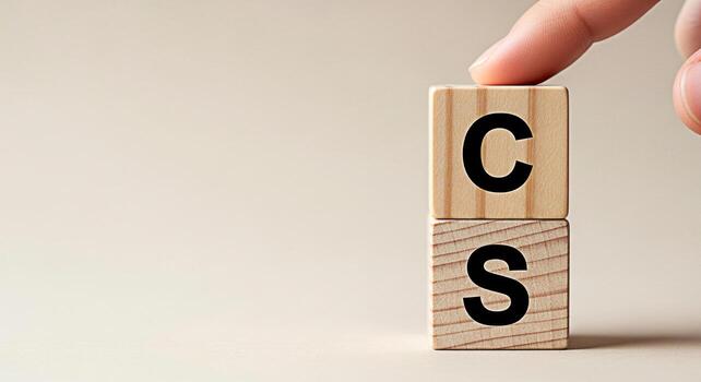 A finger touches wooden blocks stacked on a neutral surface spelling out CS symbolizing computer science customer service or creative solutions in a minimalist and conceptual composition photo