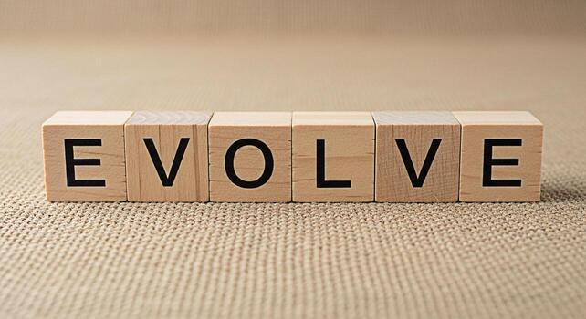 Wooden blocks spelling Evolve on a textured surface symbolizing growth and change in a neutral environment suggesting progress and adaptation for business and personal development concepts photo