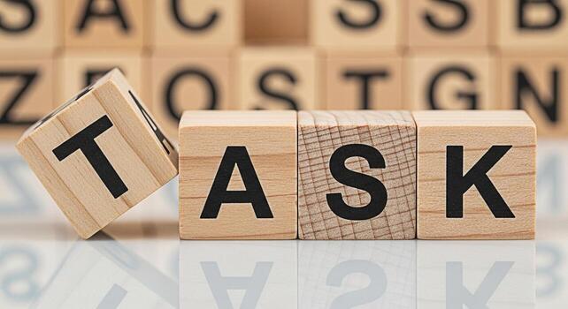 Wooden blocks spelling TASK on a reflective surface with a focus on project management and the importance of completing assignments in a timely and efficient manner to achieve success photo