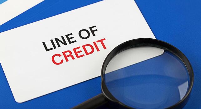 Examining a Line of Credit with a Magnifying Glass on a Blue Background representing financial scrutiny and the importance of understanding credit terms offering a clear view into financial agreements photo