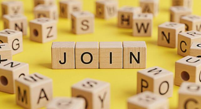 Wooden alphabet blocks spelling JOIN on a bright yellow surface surrounded by scattered letter cubes creating a playful and inviting atmosphere symbolizing teamwork collaboration and new opportunities photo