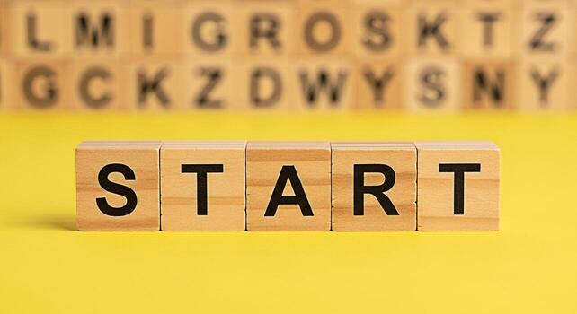 Wooden blocks spelling START on a bright yellow surface inspiring action and new beginnings with blurred alphabet blocks in the background creating a motivational and optimistic atmosphere for success photo
