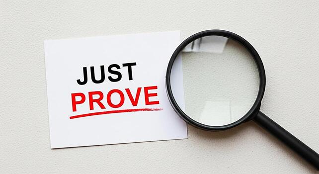 Magnifying glass examining a card with the words Just Prove on a textured surface emphasizing the need for evidence and verification in a business and legal context creating a mood of scrutiny and inv photo