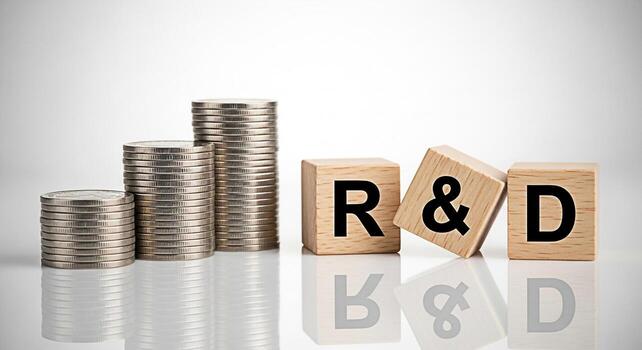 Stacks of coins and wooden blocks with RD letters representing investment in research and development on a white reflective surface symbolizing growth innovation and financial strategy photo