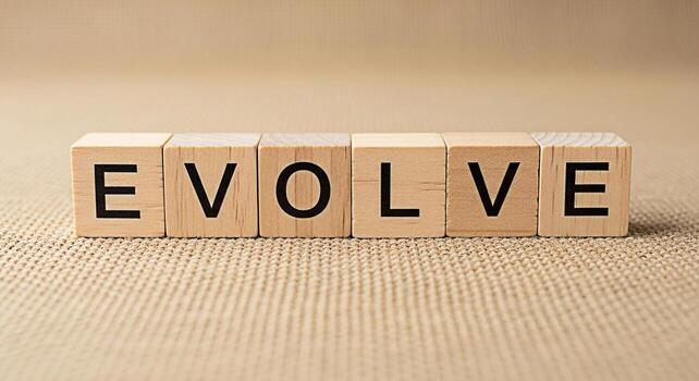 Wooden blocks spelling EVOLVE on a textured surface symbolizing growth and adaptation in a neutral setting conveying a message of positive change and continuous improvement photo