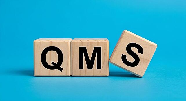 Wooden blocks displaying QMS on a vibrant blue background representing Quality Management System implementation and improvement conveying a sense of structure and systematic approach to quality assura photo