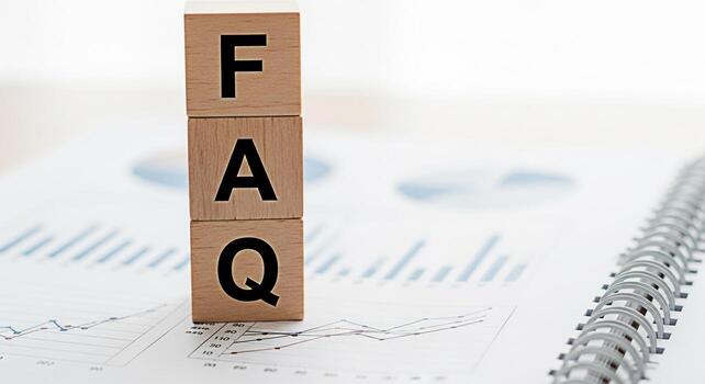 Wooden blocks spelling FAQ placed on a financial report in a bright office representing frequently asked questions and information resources for business analysis and data interpretation photo