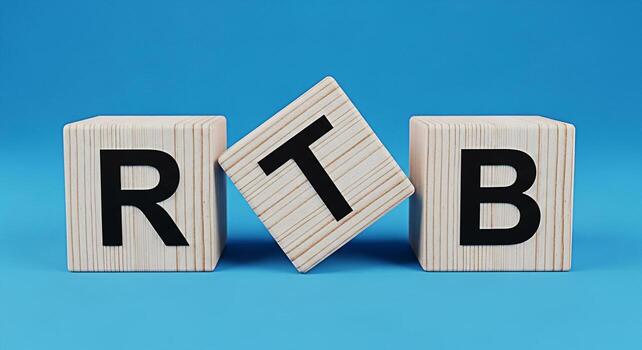Wooden blocks spelling RTB on a blue background showcasing a concept of real time bidding and programmatic advertising in a simple and clean studio setting conveying a message of innovation photo