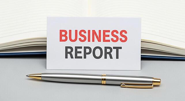 Elegant silver pen resting beside a crisp business report card on a gray desk with an open notebook in the background conveying a sense of professionalism and financial analysis photo