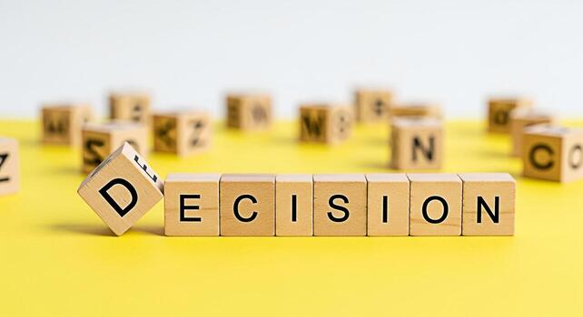 Wooden blocks spelling Decision on a bright yellow surface representing choice and determination in a business or personal context conveying a sense of strategic planning and problemsolving photo