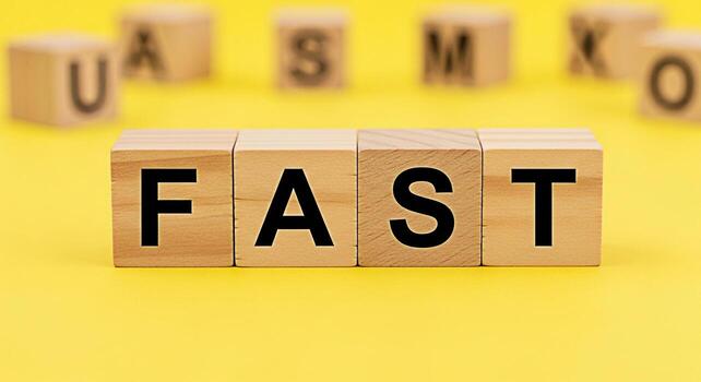 Wooden blocks spelling out the word FAST on a bright yellow background conveying a sense of speed urgency and efficiency ideal for themes related to business technology and quick solutions in a modern photo