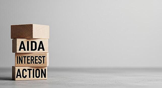 Stacked wooden blocks displaying AIDA Attention Interest Desire Action on a gray surface representing a marketing strategy in a minimalist and conceptual setting ideal for business and advertising photo