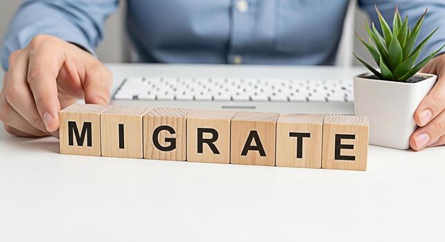 Person arranging wooden blocks spelling MIGRATE on a white desk in a bright office symbolizing business relocation data migration and the concept of moving to new systems with a modern and clean aesth photo