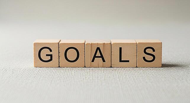 Wooden blocks spelling GOALS on a textured surface symbolizing ambition and achievement in a neutral setting representing focus and determination for personal or professional growth and success photo