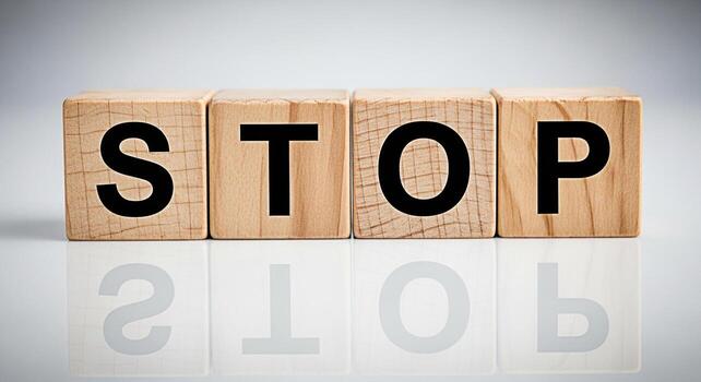 Wooden blocks spelling STOP on a reflective surface conveying a message of caution and prevention ideal for safety campaigns and awareness initiatives in a clean minimalist setting photo