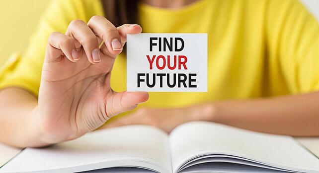 Person holding a card with the text Find Your Future in a bright cheerful setting symbolizing hope and inspiration for career planning and personal development with an open book photo