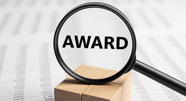 Closeup of a magnifying glass focusing on the word Award placed on wooden blocks against a background of financial documents symbolizing achievement and recognition in a business environment photo