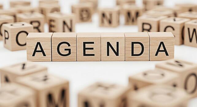 Wooden blocks spelling Agenda on a white surface surrounded by other lettered blocks representing planning and organization in a business meeting or project management conveying a sense of structure a photo