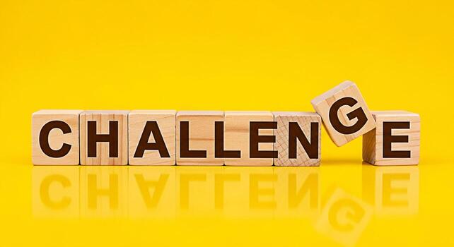 Wooden blocks spelling Challenge with a G falling symbolizing overcoming obstacles and embracing change on a bright yellow background representing motivation and the pursuit of success photo