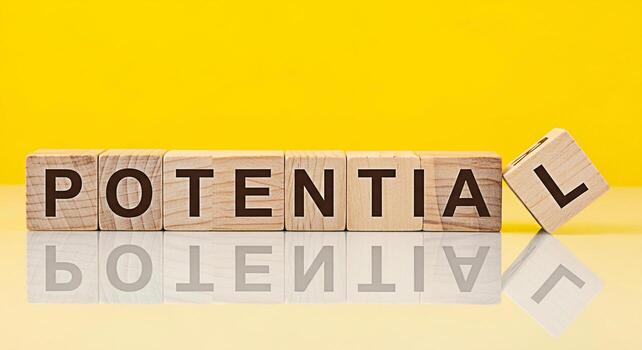 Wooden blocks spelling Potential on a reflective surface against a bright yellow background symbolizing growth opportunity and the realization of untapped abilities in a positive and encouraging envir photo