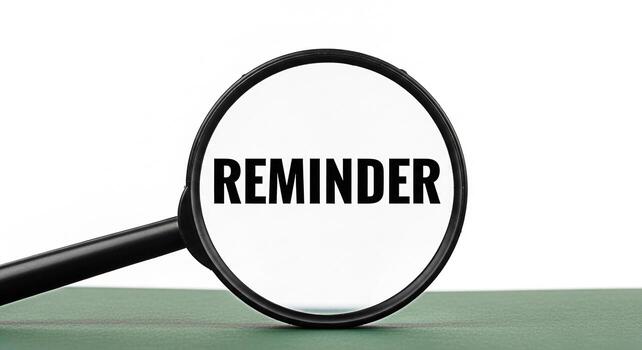 Magnifying glass focusing on the word Reminder on a green surface emphasizing the importance of remembering tasks and deadlines in a professional and organized environment promoting productivity photo