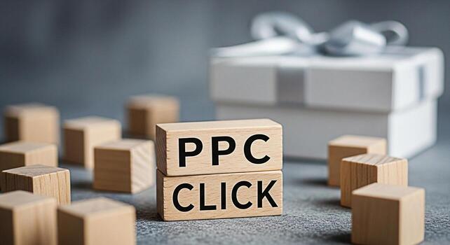 Wooden blocks displaying PPC Click message on a gray surface with a gift box in the background representing payperclick advertising and online marketing success with a focus on business growth photo