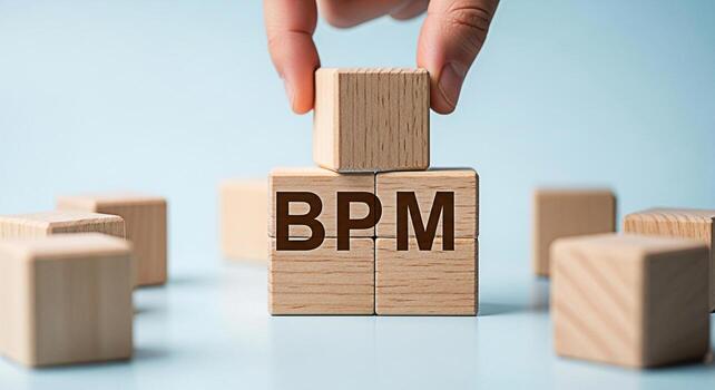 Hand placing a wooden block on top of BPM Business Process Management blocks in a bright studio setting symbolizing efficiency optimization and strategic business process improvement photo