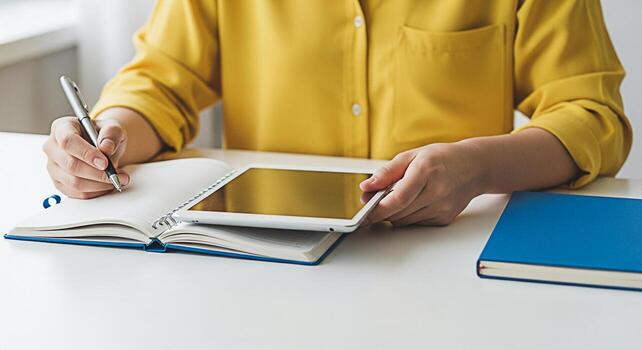 Focused student in a bright room writing notes in a notebook while holding a tablet showcasing a blend of traditional and modern learning methods for effective study and creative inspiration photo