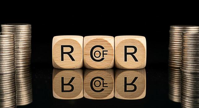 Wooden dice spelling out ROR Return on Risk surrounded by stacks of coins on a reflective black surface symbolizing financial investment and risk management strategies in a business context photo