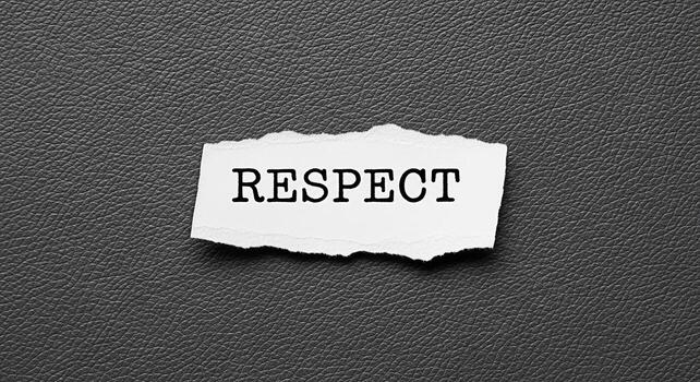 The word Respect printed on a torn piece of white paper placed on a dark textured surface symbolizing the importance of treating others with dignity and consideration in all aspects of life photo