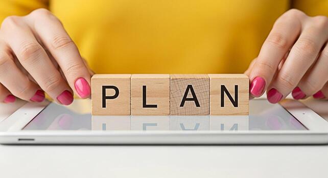 Womans hands arranging wooden blocks spelling PLAN on a tablet symbolizing strategic planning and organization in a modern techsavvy environment conveying a sense of focus and proactive decisionmaking photo