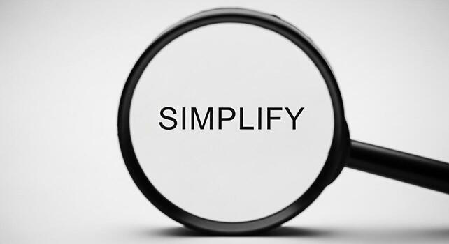 Magnifying glass focusing on the word Simplify against a clean white background symbolizing clarity focus and the importance of streamlining processes for efficiency and problemsolving in business and photo