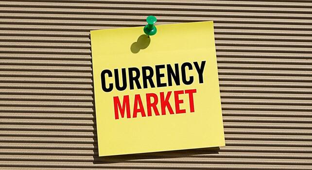 Bright yellow sticky note displaying Currency Market pinned on a corrugated cardboard surface conveying a message about financial trading and global economics in a simple yet impactful way symbolizing photo