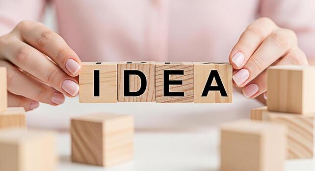 Womans hands arranging wooden blocks spelling IDEA on a white surface symbolizing creativity and innovation in a bright clean environment fostering a sense of inspiration and problemsolving photo
