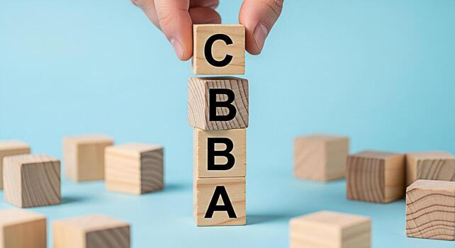 Hand stacking wooden blocks with the letters C B and A on a light blue background representing grading assessment or quality control in an educational or business setting conveying precision and evalu photo