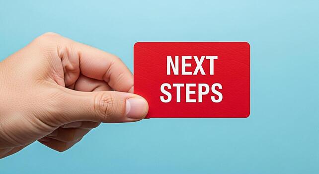 Human hand holding a red card with the words Next Steps against a blue background symbolizing progress planning and a clear path forward in business and personal development photo