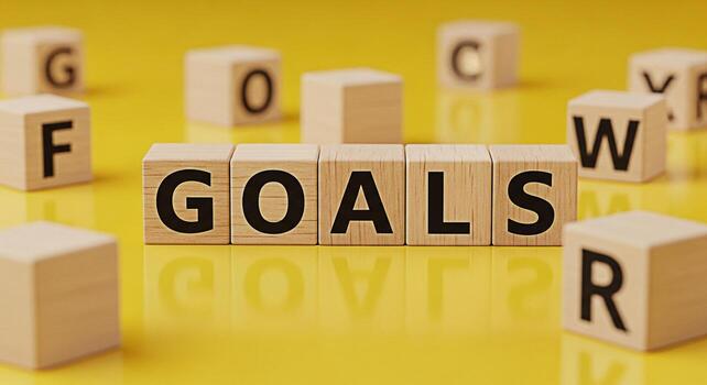 Wooden blocks spelling GOALS on a yellow surface surrounded by other lettered blocks representing ambition and determination in a bright and optimistic setting symbolizing success and achievement photo