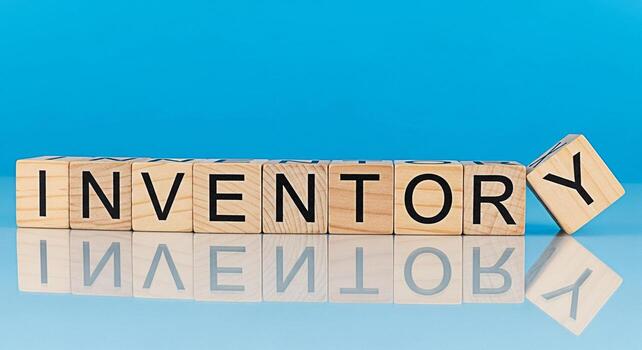 Wooden blocks spelling INVENTORY on a reflective surface against a blue background representing stock management and supply chain efficiency with a focus on organization and control photo