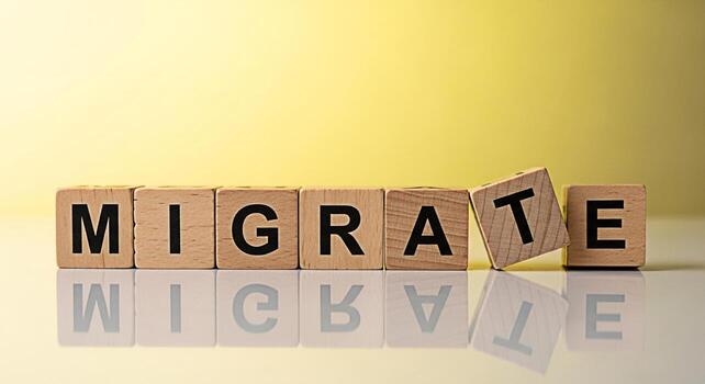 Wooden blocks spelling MIGRATE on a reflective surface against a yellow background symbolizing relocation change and the concept of moving to a new place or adapting to a different environment with an photo