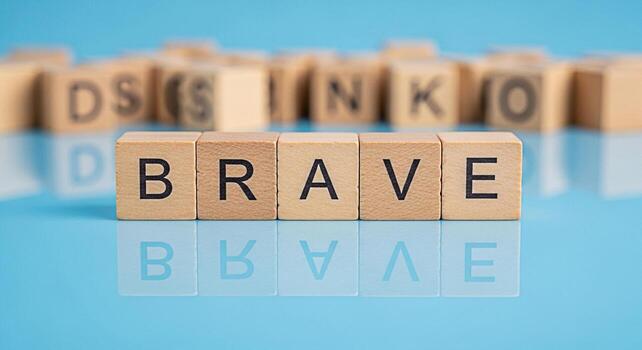 Wooden blocks spelling the word BRAVE on a reflective blue surface symbolizing courage and resilience in a challenging environment promoting a message of strength and determination photo